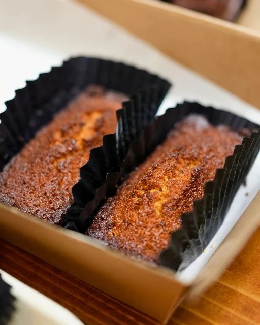 Classic financiers in black fluted cases in a kraft box at Wild Honey Pie
