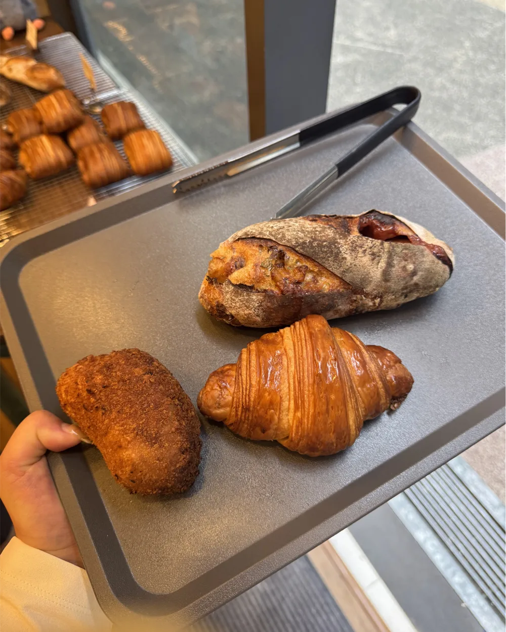 A customer carrying a self-service tray of bakes at the Wild Honey Pie counter