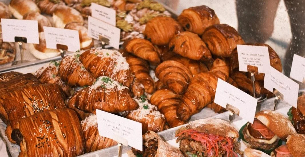 Trays of croissants, pain suisse and sandos at the Wild Honey Pie counter, each with a hand-written price card